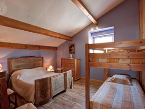 Ein Schlafzimmer mit einem Holzbett, einem Einzelbett, einem Schminktisch, einem Nachttisch und einem Fenster.