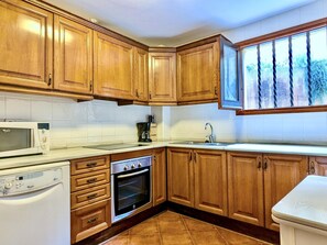 A kitchen with wooden cabinets, a microwave, a dishwasher, and an oven. - House, sea view - 5 guests (Tossa de Mar)