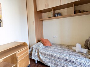 A small, single-bed room with a wooden desk, a shelf with decorative items, and a patterned bedspread. - House, sea view - 5 guests (Tossa de Mar)
