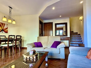 A living room with a sofa, a coffee table, and a dining area with chairs and a table. - House, sea view - 5 guests (Tossa de Mar)