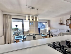 A modern hotel room with a dining area, a sofa, a lamp, and a view of the outdoors. - Apartment with panoramic view, pets welcome - 9 guests (Tossa de Mar)