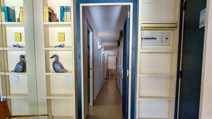 Un corridoio con scaffali aperti su entrambi i lati, una sedia in primo piano e una porta alla fine.