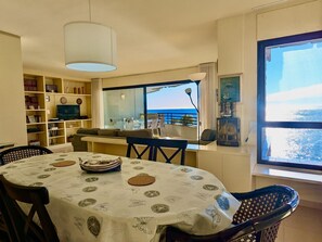 Ein Essbereich mit einem Tisch für zwei Personen, einer Couch und einem Fernseher im Hintergrund.