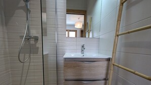 Ein modernes Badezimmer mit Duschkabine aus Glas, einem Holzwaschtisch mit Waschbecken und einer Bambusleiter.