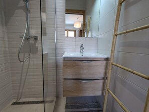 Ein modernes Badezimmer mit Duschkabine aus Glas, einem Holzwaschtisch mit Waschbecken und einer Bambusleiter.