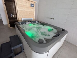 A hot tub with a wooden panel wall and a tiled floor. - Mountain lodge with valley view (Le Val-d'Ajol)