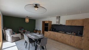 Eine moderne Küche mit Holzschränken, einem Essbereich inklusive Tisch und Stühlen sowie einem Deckenventilator.