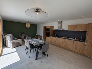 Eine moderne Küche mit Holzschränken, einem Essbereich inklusive Tisch und Stühlen sowie einem Deckenventilator.
