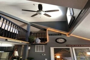 A staircase with a ceiling fan, a clock, and a sign that reads 'WINTER'. - Lazy Duck Cottages The Whole Flock In One Booking (Duck Creek Village)