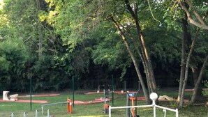Zona d'exercici a l'aire lliure amb diferents aparells de fitness, envoltada d'arbres i una tanca.