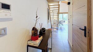 Ein Flur mit Holzboden, einem Tisch mit Büchern und einem dekorativen Zweig, und einer Schiebetür zu einem Zimmer mit Blick.