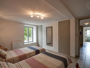 A bedroom with two beds, a window, a door, and a hallway leading to another room. - Modern lodge in natural surroundings - 4 guests (Usson-en-Forez)