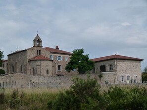 A stone building with a bell tower, possibly a historical site or church, surrounded by greenery and a fence. - Modern lodge in natural surroundings - 4 guests (Usson-en-Forez)
