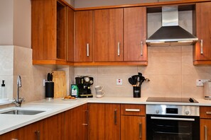 Eine Küche mit Holzausstattung, einer Edelstahl-Dunstabzugshaube, einer Kaffeemaschine und einem Toaster.