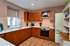 Eine moderne Küche mit Holzschränken, einem Bosch-Ofen, einem weißen Kühlschrank und einem Fenster, das für natürliches Licht sorgt.