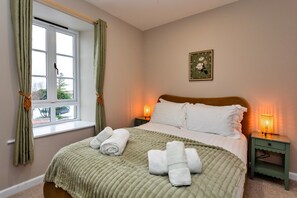 Una camera da letto con un letto, due comodini, una finestra con tende e un quadro appeso al muro.