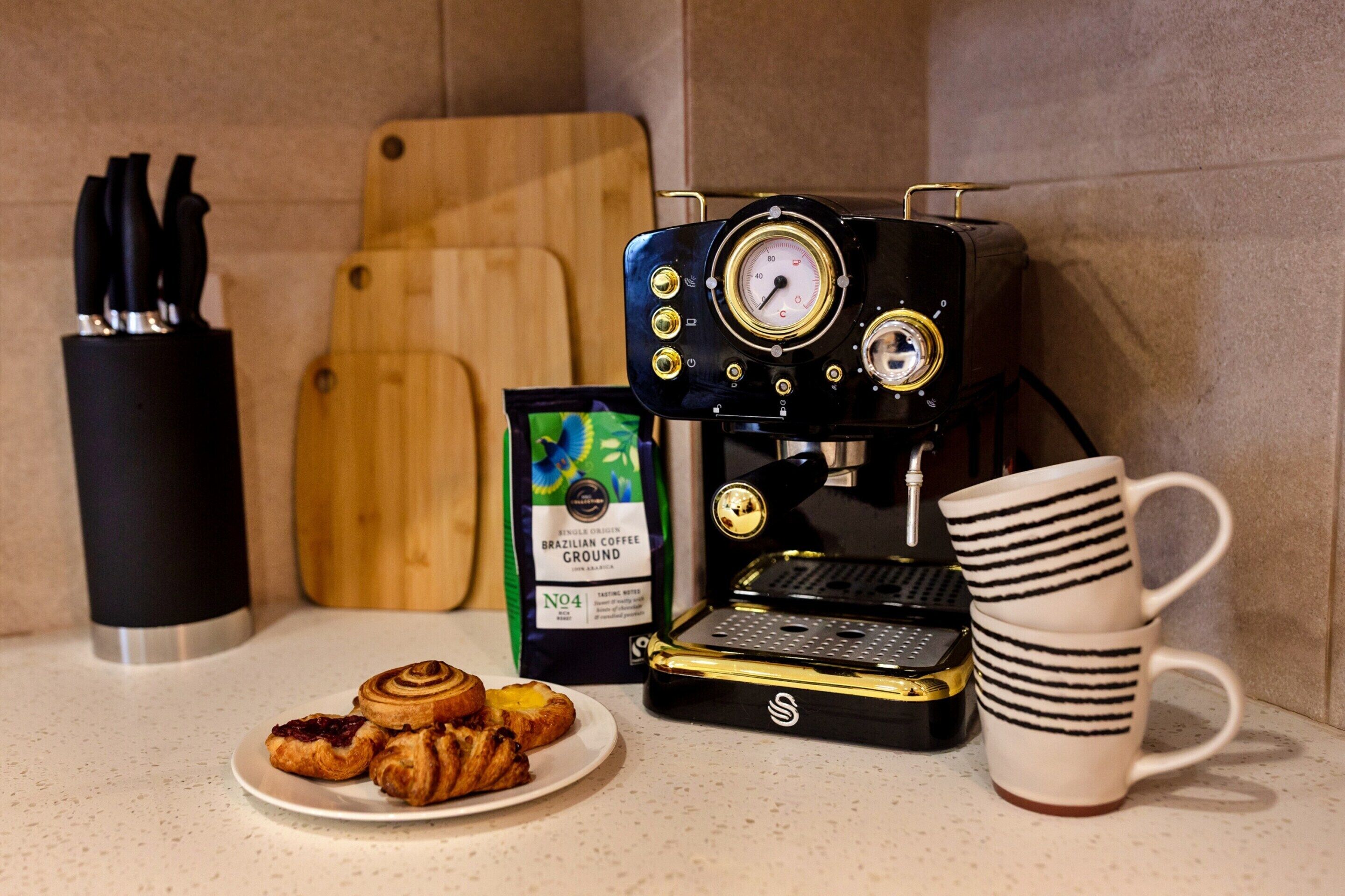 A coffee machine, a mug, and pastries on a countertop.