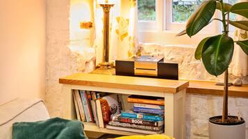 A cozy reading nook with a bookshelf, a lamp, and a potted plant.