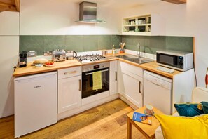 A compact kitchen with white cabinets, a Bosch dishwasher, a built-in oven, a microwave, and a coffee maker. - Romantic Lyme Regis Couple's Hideaway (Lyme Regis)