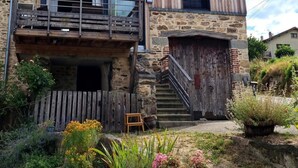 Ein rustikales Steinhaus mit einem Holzbalkon und einer Treppe, die zu einer Tür führt.