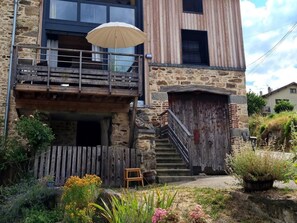 A rustic stone building with a wooden balcony and a staircase leading to a door. - Welcoming gîte, pets allowed - 5 guests (Doizieux)