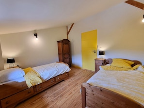 A room with two wooden beds, a wardrobe, a yellow door, and a lamp on a bedside table. - Welcoming gîte, pets allowed - 5 guests (Doizieux)