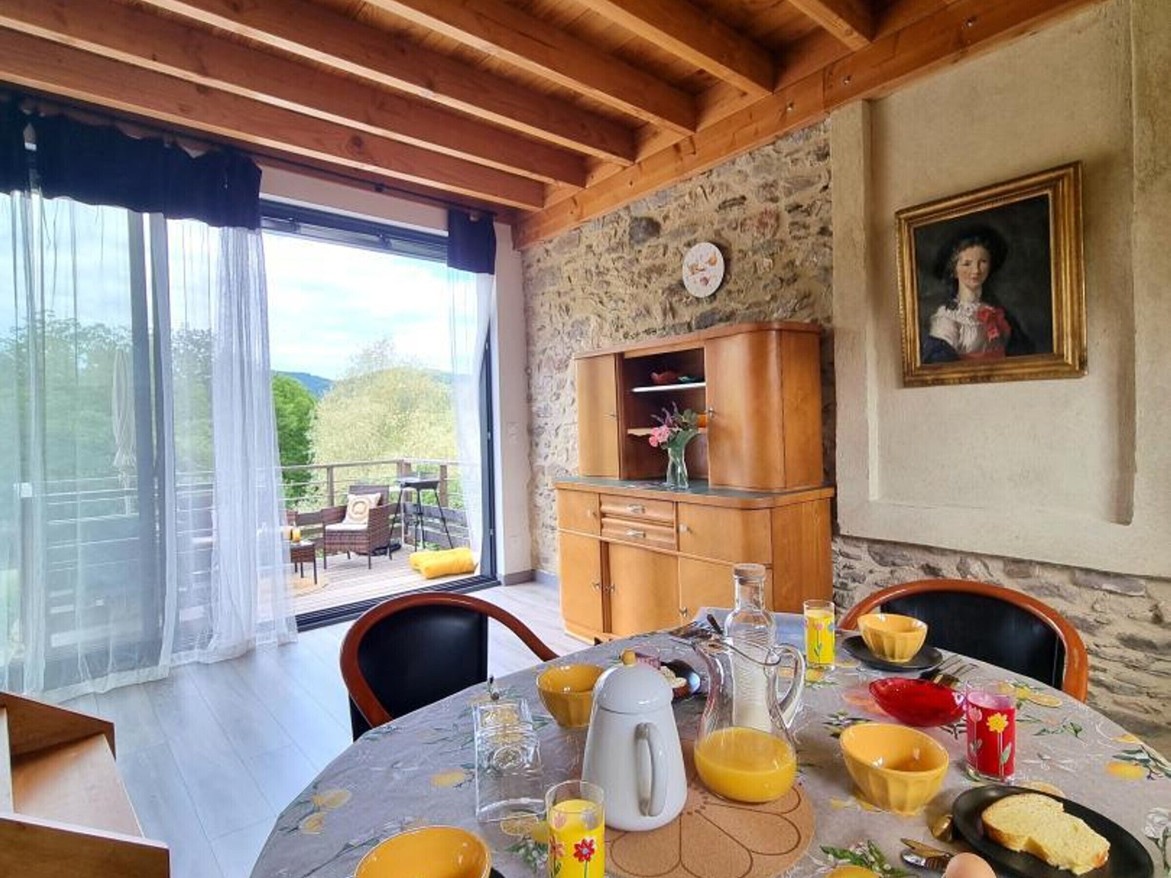 A dining area with a table set for breakfast, a stone wall, and a view of the outdoors.