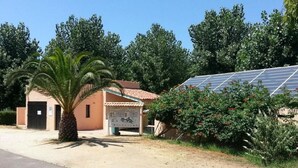 Ein Gebäude mit einer Solaranlage, einer Palme und einem Schild.