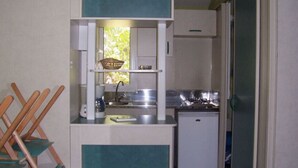 Uma cozinha compacta equipada com pia, fogão e uma pequena geladeira.