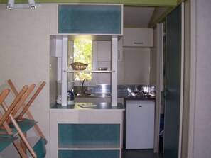 Eine kleine Küchenzeile mit Spüle, Herd und kleinem Kühlschrank.