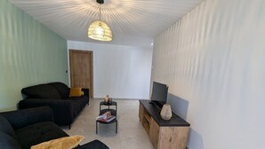 En stue med sofa, sofabord, TV-møbel og en hængende lampe.