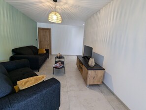 Ein Wohnzimmer mit einer Couch, einem Couchtisch, einer TV-Konsole und einer Hängelampe.
