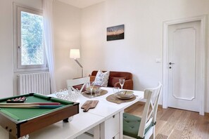A room with a pool table, dining table, and chairs. There is a window with curtains, a lamp, and a door. - URNEST Colli - 1 bedroom apartment in the first hills surrounding Bologna (Bologna)