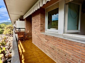 A covered outdoor area with a brick wall, a window, and a table with chairs. - Apartment with pool, pets OK - 6 guests (Tossa de Mar)