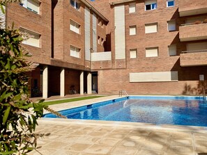 A multi-story brick building with a swimming pool. - Apartment with pool, pets OK - 6 guests (Tossa de Mar)