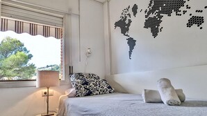 Makuuhuoneessa on sänky, lamppu, maailmankartta-aiheinen seinätaulu ja ikkuna, josta avautuu näkymä puihin.