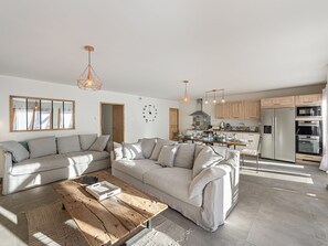 Ein modernes Wohnzimmer mit einer Eckcouch, einem Holztisch und einer Küche im Hintergrund.