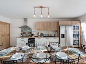 Eine moderne Küche mit Holzausstattung, einem Edelstahlkühlschrank und einem Essbereich, der für eine Mahlzeit gedeckt ist.