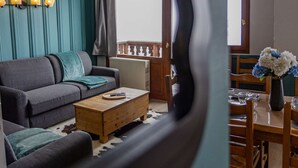 A living room with a sofa, coffee table, and a dining area with chairs and a vase of flowers. - Cozy apartment, panoramic view - 8 guests (Belle Plagne)