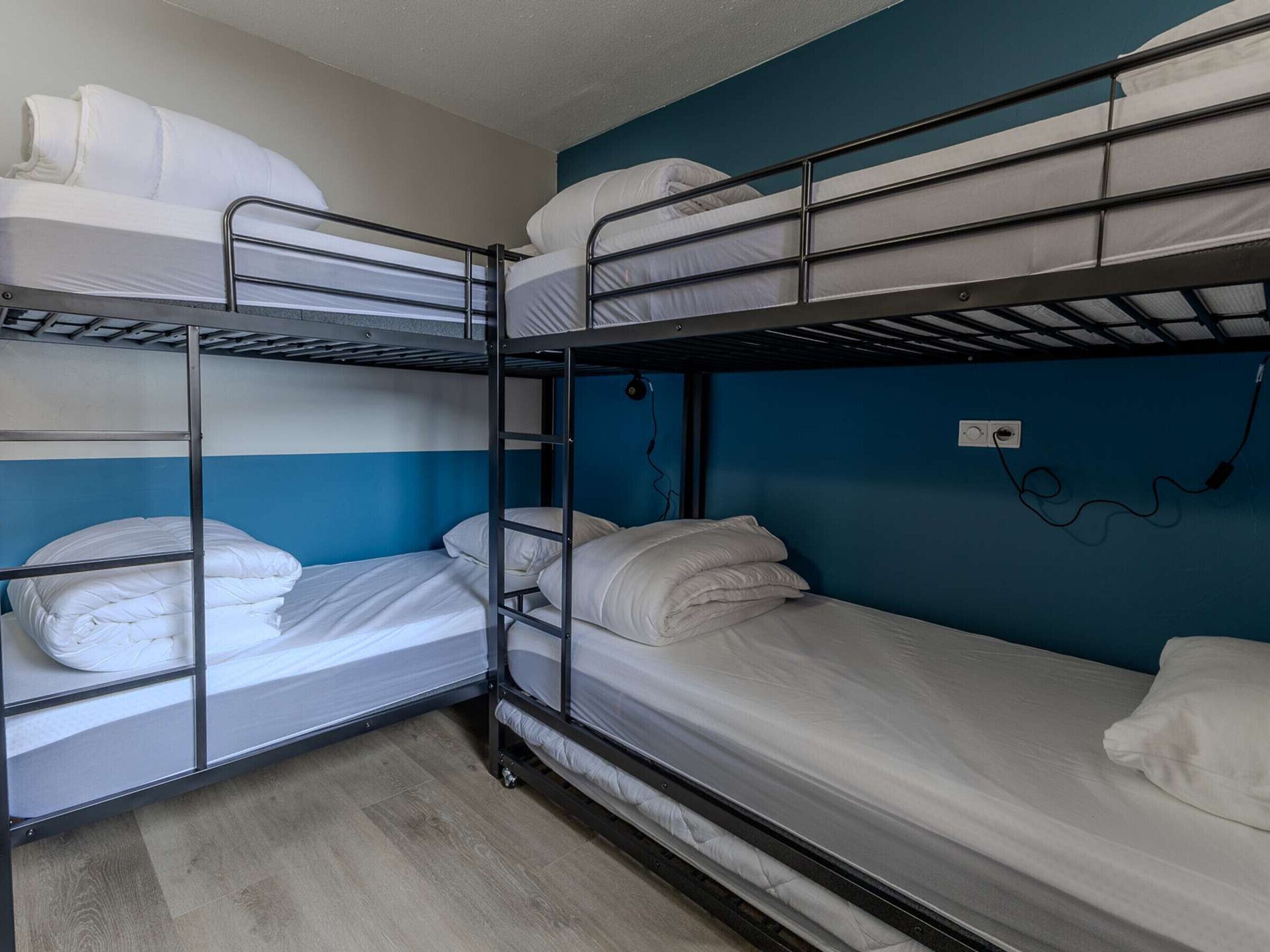 A bunk bed room with a blue wall and a power outlet.