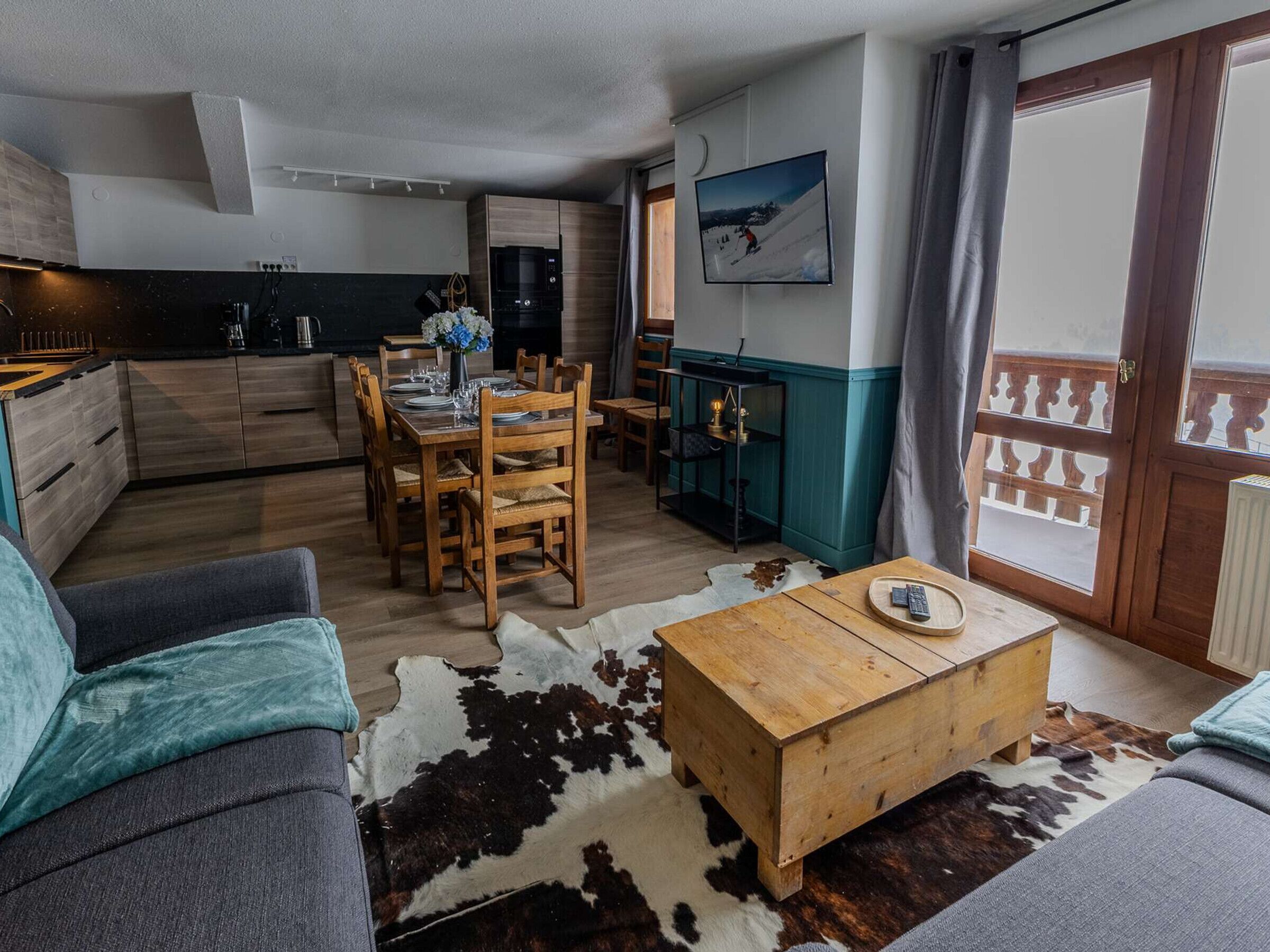 Una sala de estar moderna con un sofá, una mesa de centro de madera y un comedor con mesa dispuesta para cuatro.