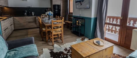 Una sala de estar moderna con un sofá, una mesa de centro de madera y un comedor con mesa dispuesta para cuatro.