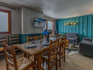 Ein Essbereich mit einem Holztisch, gedeckt für sechs Personen, umgeben von Stühlen, und ein Wohnbereich mit einer Couch und einem Kuhfellteppich.