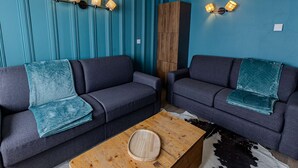 A modern living room with two dark sofas, a wooden coffee table, and teal walls. - Cozy apartment, panoramic view - 8 guests (Belle Plagne)