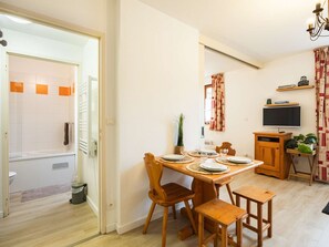 A compact living space with a dining area, a television, and a small kitchenette. - Cozy apartment - 4 guests (Vignec)