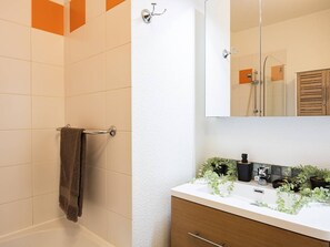 A bathroom with a white sink, a mirror, a towel rack, and a shower area. - Cozy apartment - 4 guests (Vignec)