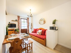 Espaço compacto com área de refeições, sofá, pequeno espaço de cozinha e um espelho na parede.
