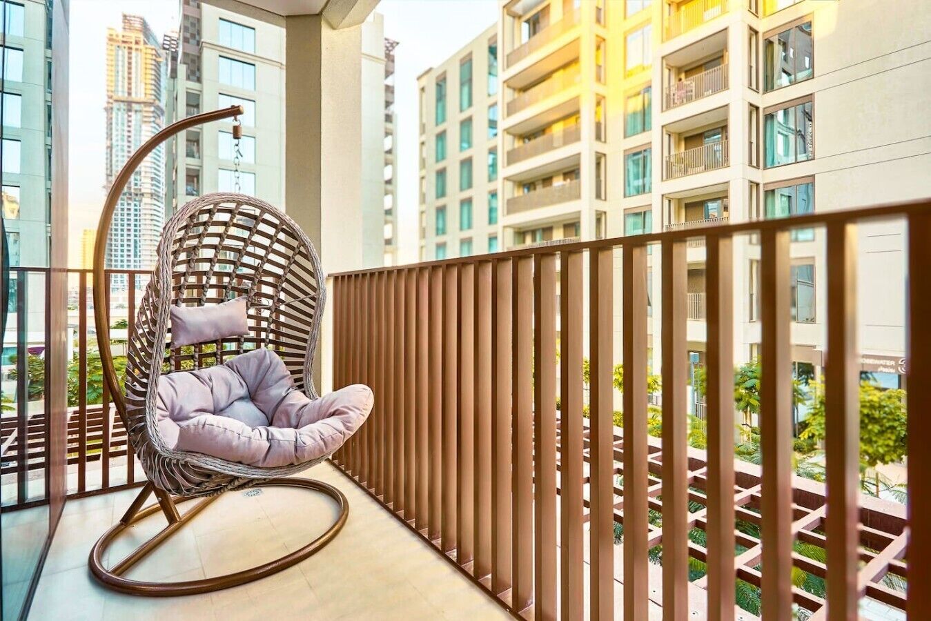 Een balkon met een rieten stoel en uitzicht op hoge gebouwen.