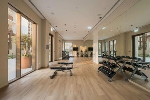 Ein großzügiger Fitnessraum mit Cardiogeräten, Kraftmaschinen und einer großen Spiegelwand.
