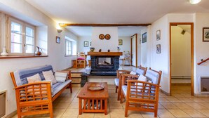 A cozy living room with a fireplace, wooden furniture, and a tiled floor.